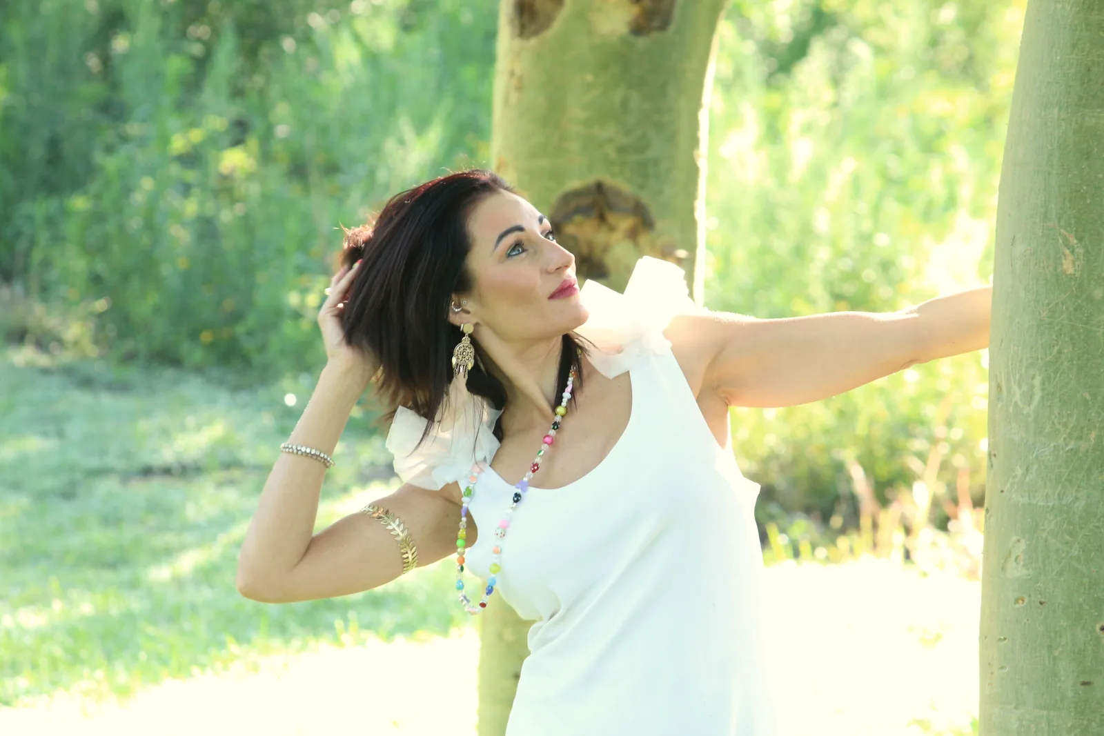Jullie-Ann Viljoen in a white dress beside a tree, looking up into the light