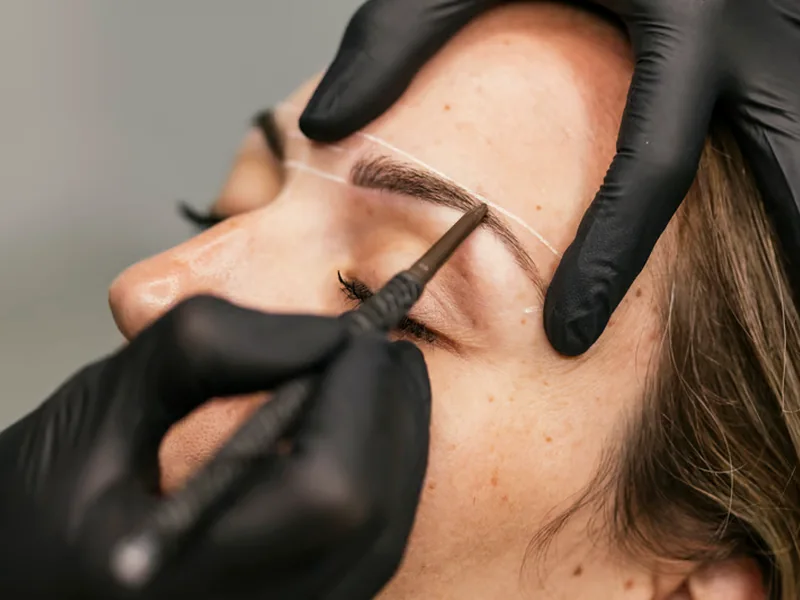 A brow being mapped and shaded with a fine permanent makeup tool